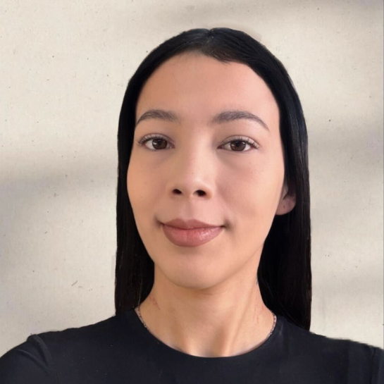 Portrait of Vanessa Navarro, a young woman with sleek black hair, dressed in a black top, standing against a neutral background.