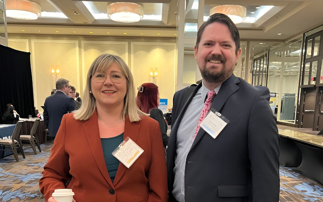 Olga Prygoda attending a professional conference, standing beside a colleague in a business setting.